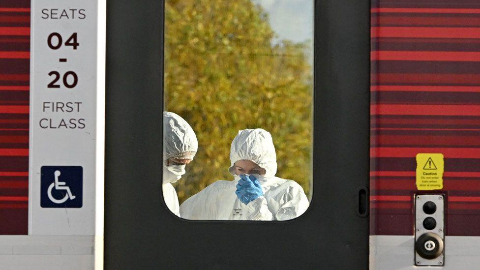 A forensic police officer examines the LNER train as it sits in Huntingdon Station after a stabbing attack on November 02, 2025 in Huntingdon, England