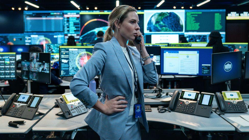 Rebecca Ferguson in A House of Dynamite, surrounded by screens, talking on the phone