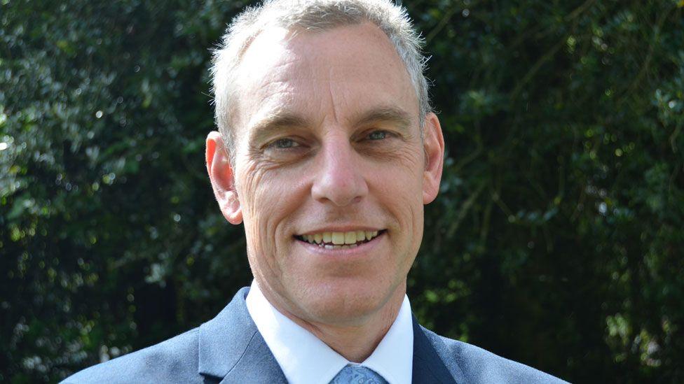 Smiling man in light blue suit. 