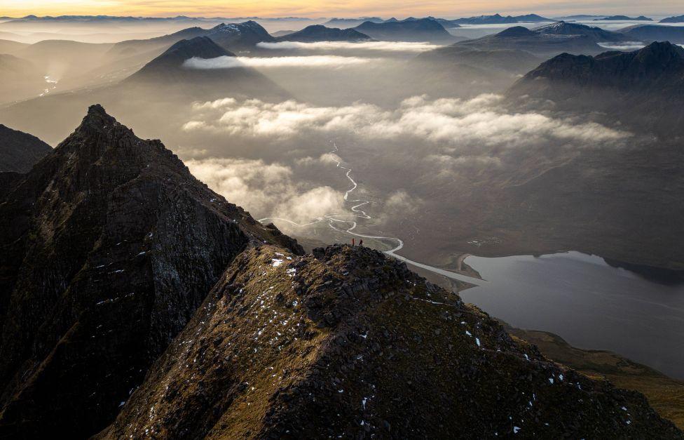 An aerial view of An Teallach, a mountain, with clouds swirling around it 