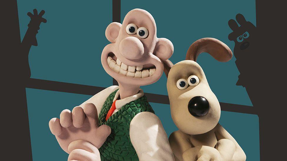 Wallace and Gromit standing back to back in front of a window with shadows of their enemies