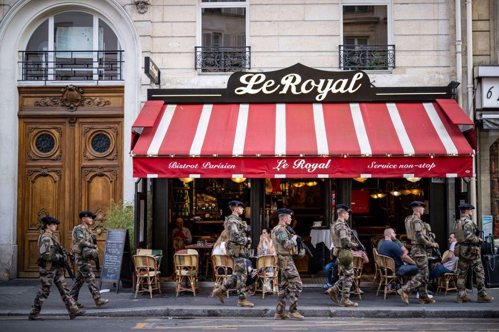 French military armed forces walk by a crowded restaurant ahead of Paris 2024 Olympic Games  on July 18, 2024 in Paris, France.