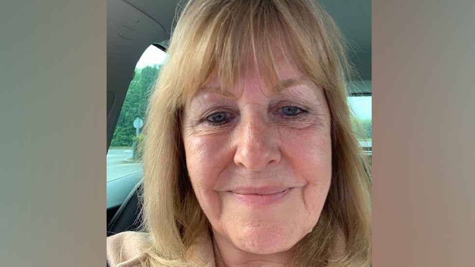 Pensioner Gail Impey smiles in a selfie in a car, she has blonde hair and a fringe