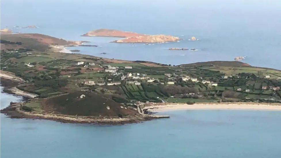 A view of Isles of Scilly from the sky, with golden beaches and green fields.