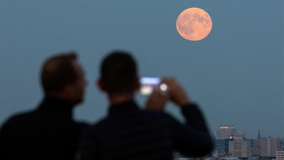 supermoon over germany, two people try to photograph it