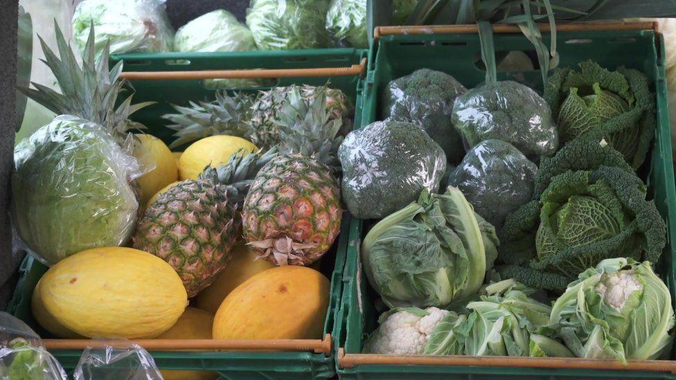 Green crates containing brocolli, cabbages, cauliflowers, lettuce, pineapples and honeydew melons 