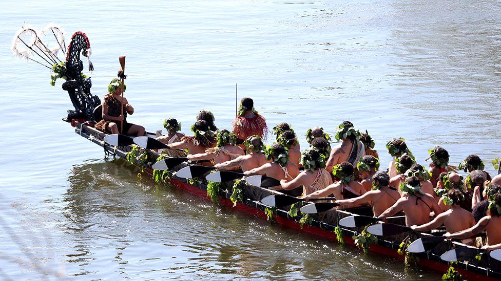 Maori warriors wearing wraeths on their heads wait in a boat on a river to carry the remains of Māori King Tuheitia Pōtatau Te Wherowhero VII to Mount Taupiri during his burial ceremony in New Zealand on 5 September