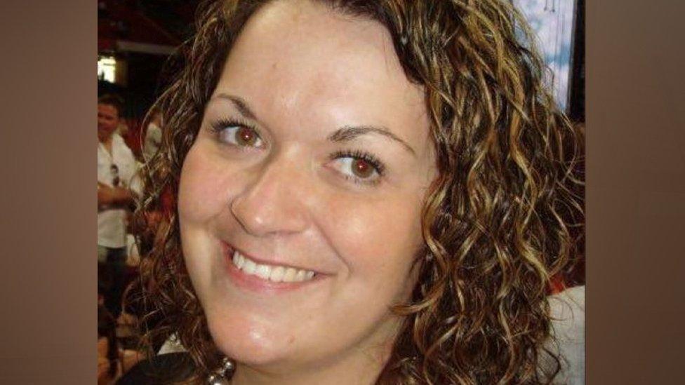 A woman with curly brown hair smiles at the camera.