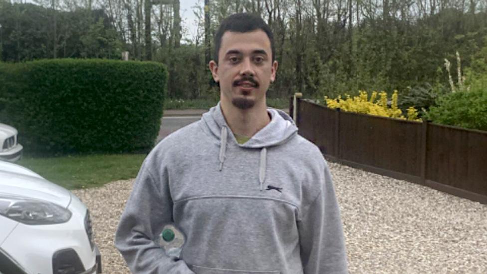 Brandon Fritz-Kessler standing on a driveway in a grey hoodie