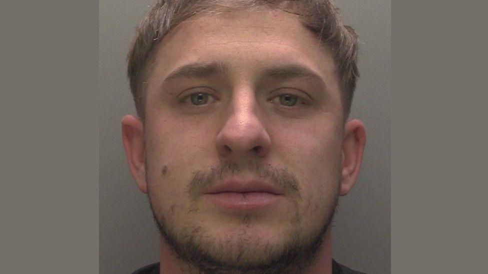 Police mugshot of Connor Whiteley with moustache and beard