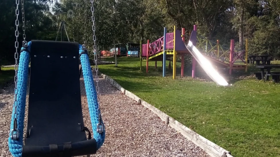 A general view picture of the adventure playground, with a swing and slide in view.