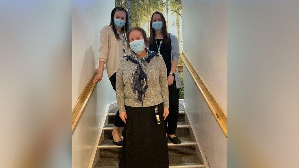 Pauline on a stairwell with two members of staff during Covid in 2020