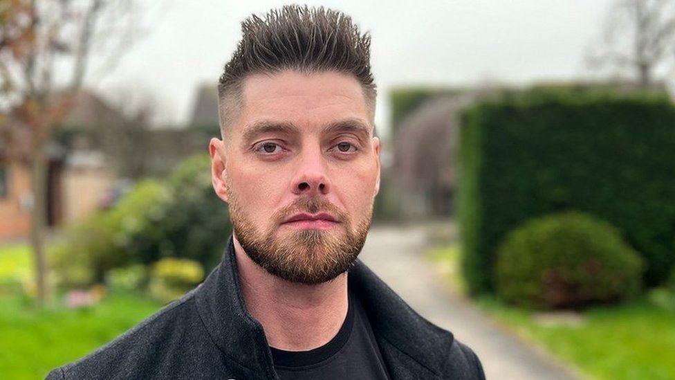 Stephen Jenkinson, who has a short beard and spiky dark hair, looks straight at the camera