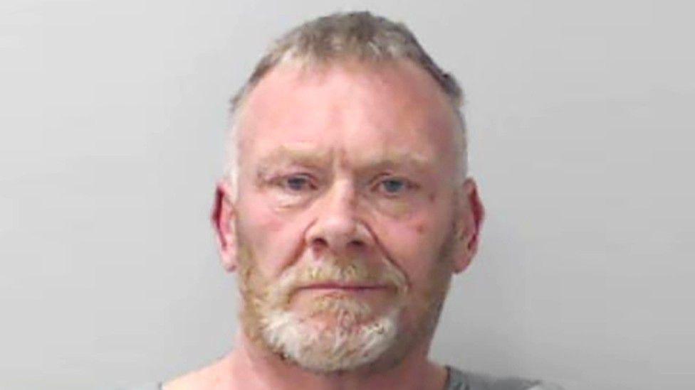 Alan Johnston looking at camera in police mugshot.