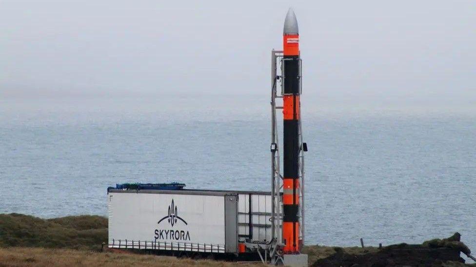 Rocket next to a Skyrora sign, with sea in the background.