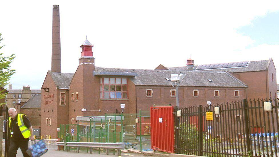The brewery is made of redy brown bricks and it has a tall chimney.