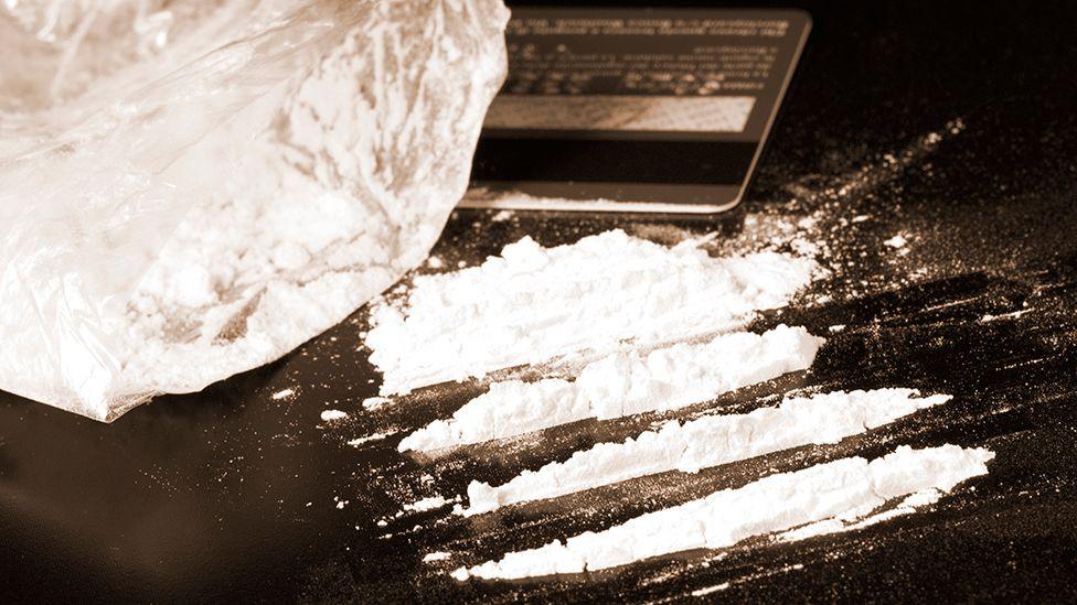Stock image of lines of cocaine on a black table with a bank card.