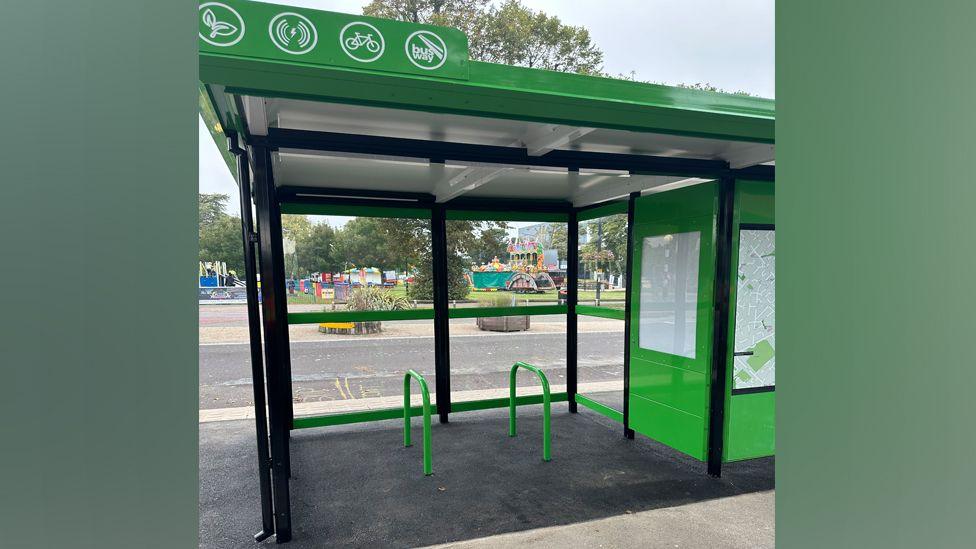 Two green cycle rails inside a bus shelter