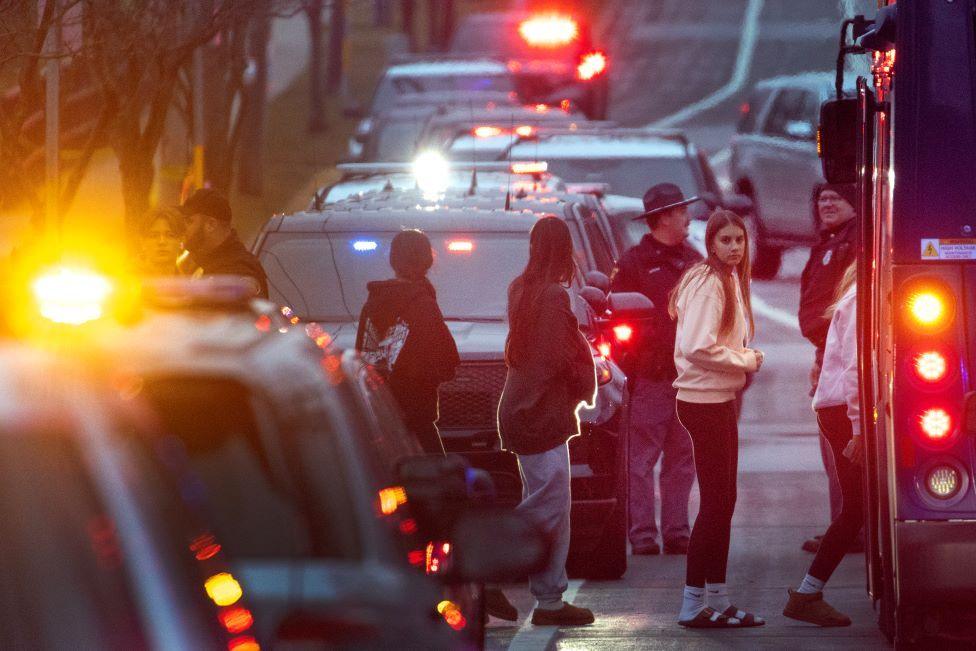 Students are escorted from a church next to the Abundant Life Christian School and taken by bus to a reunification center