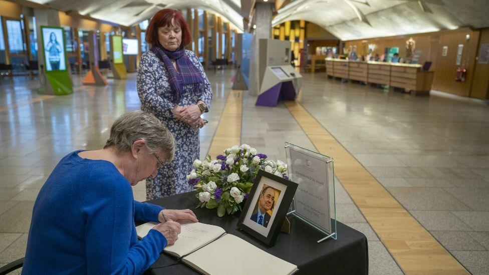 A woman signs the book of condolence for Alex Salmond in the Scottish Parliament 