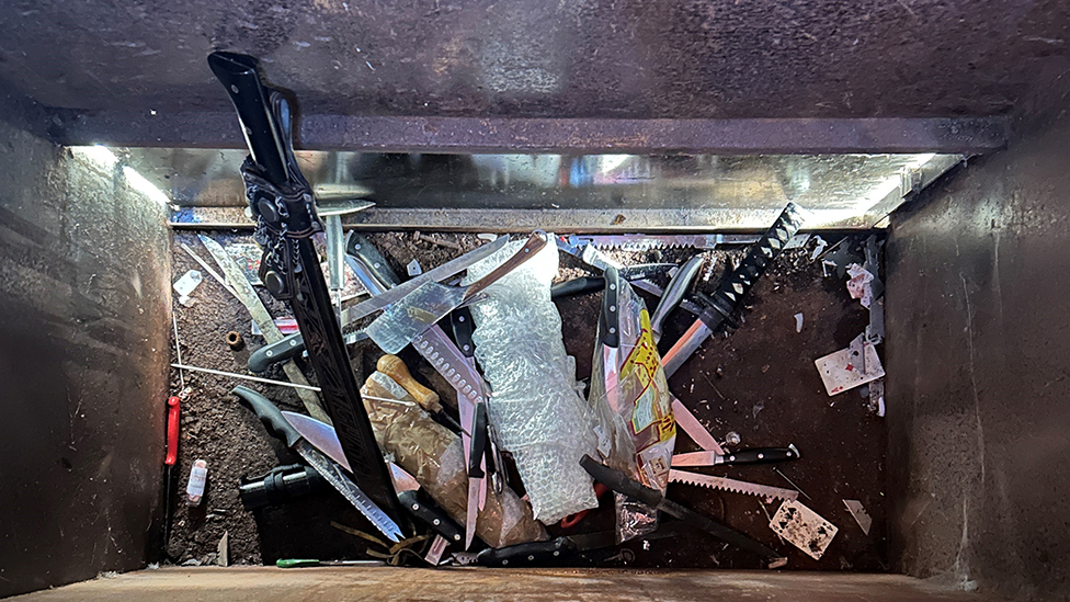 Aerial view of knives and swords in an amnesty bin, some of them more than a foot long