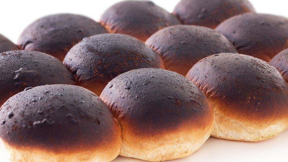 Twelve morning rolls with burnt blackened tops still attached together