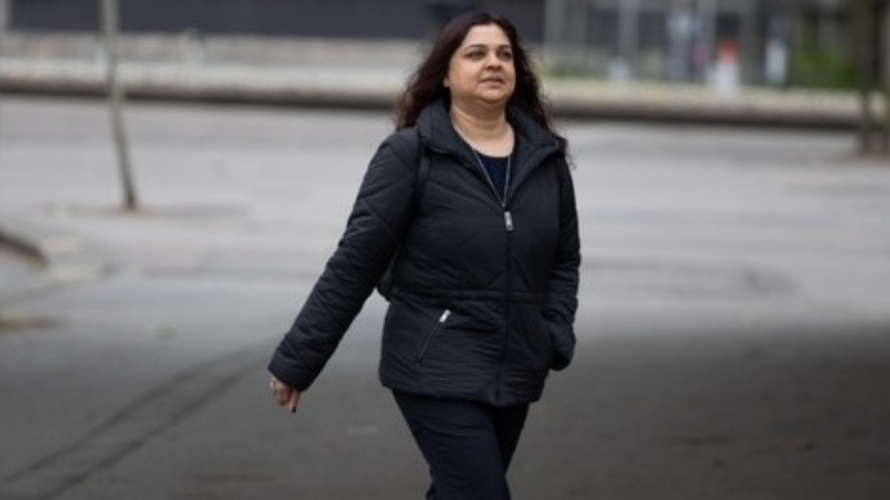 Tanya Nasir walking across road to court in black coat