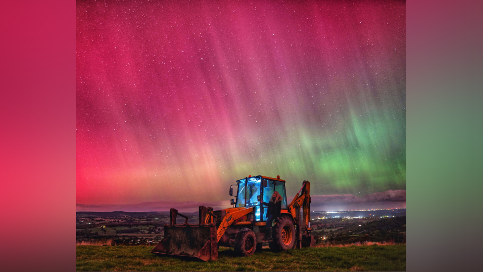 A digger at a farm and a mix of a red, pink, orange and green Northern Lights lit sky.