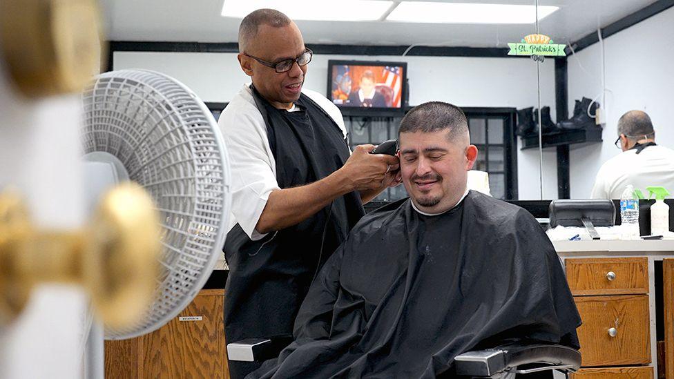 Kevin Smith(left) is an inmate at Estelle Supermax Penitentiary. He can be seen clippering the hair of a member of the prison staff in the prison's barber salon. 