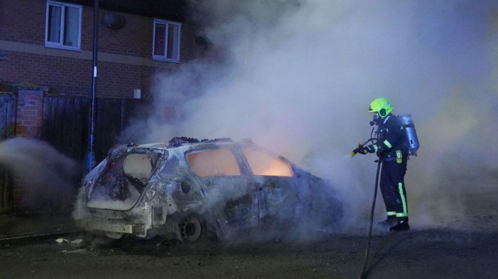 A firefighter extinguishing a car fire in Hartlepool following the riot.