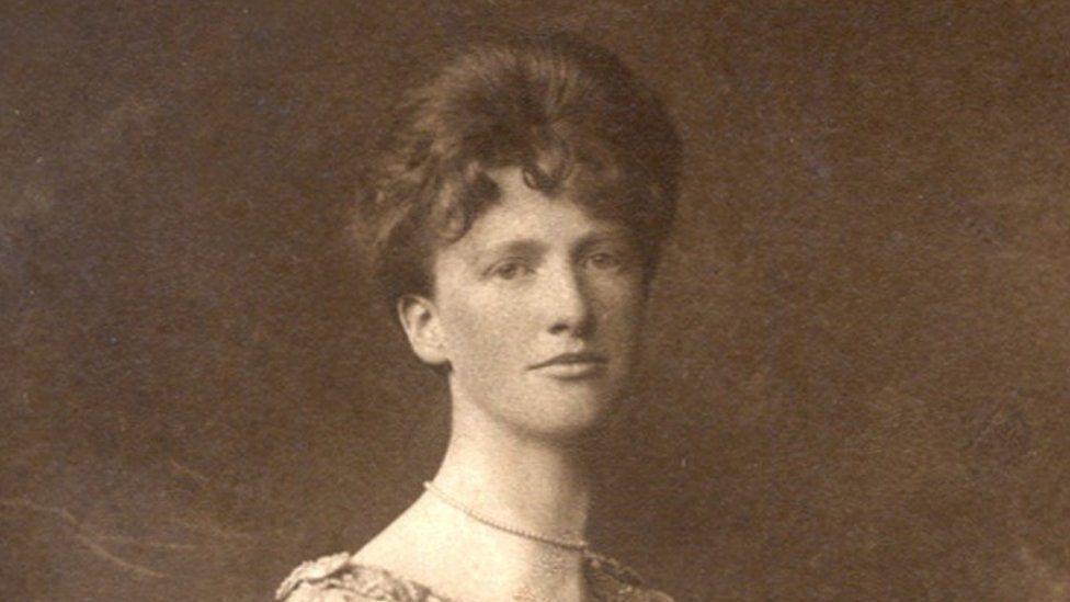 A black and white photo of a woman with her hair up, wearing a pearl choker