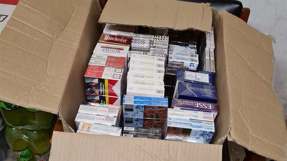 A cardboard box filled with packets of counterfeit cigarettes