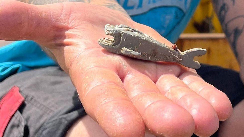 Richard West's open hand in which lies the sea-worn grey Lego shark