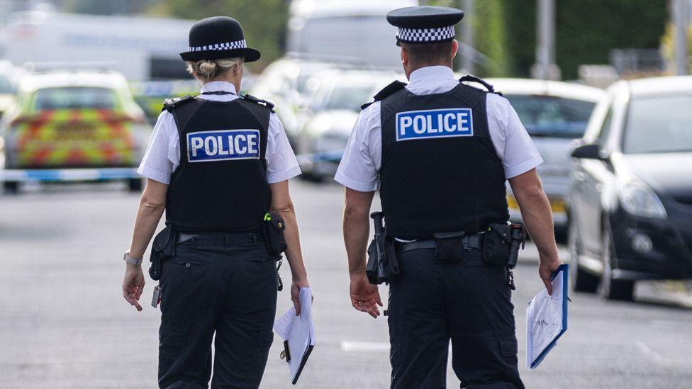 Police officers at the scene carrying clipboards