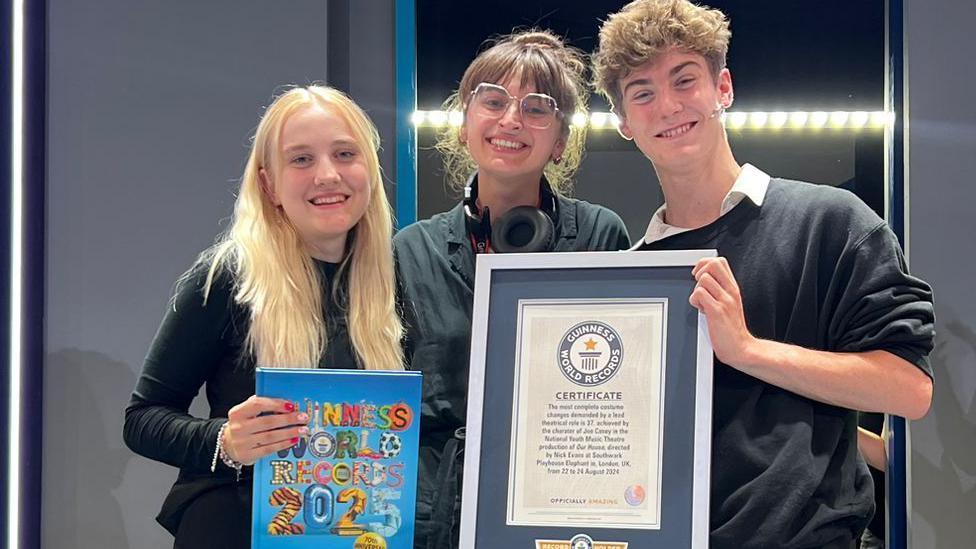 The winning actor Des Coghlan-Forbes, right, with costume designer Molly Fraser, centre, and wardrobe assistant Lucy Vickers, holding their world record certificate and the 2025 edition of the Guinness World Records