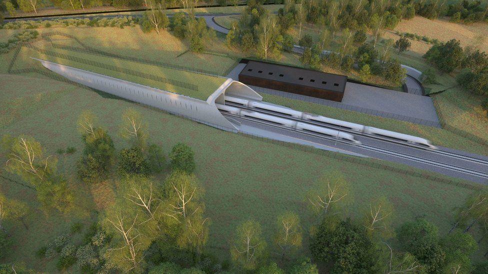 An aerial image of an animated artist impression of how the tunnel will look. Two white trains are out of focus, as they are depicted travelling out, or into, a tunnel, which is blended into the green landscape.