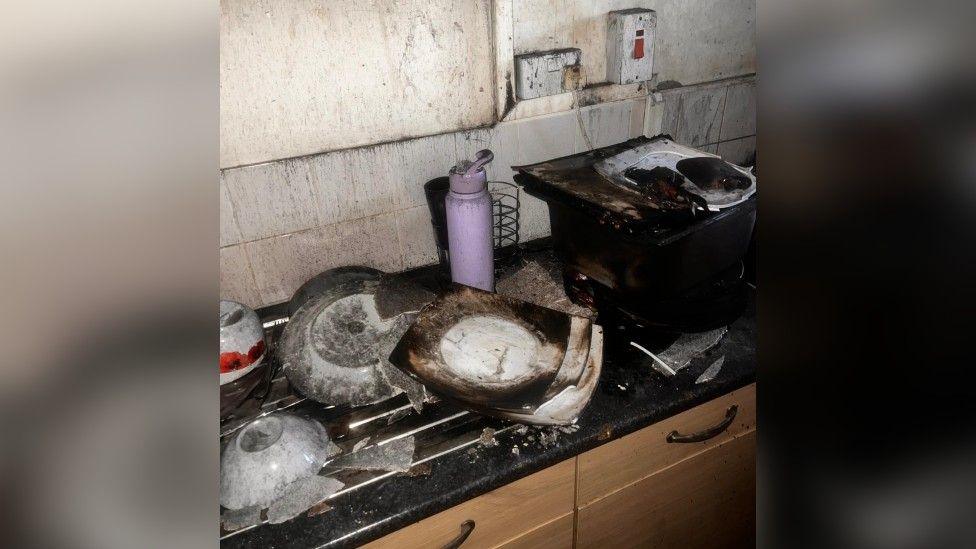 Dionne's kitchen after the fire. Plates and appliances are burnt and there is black residue on the walls.