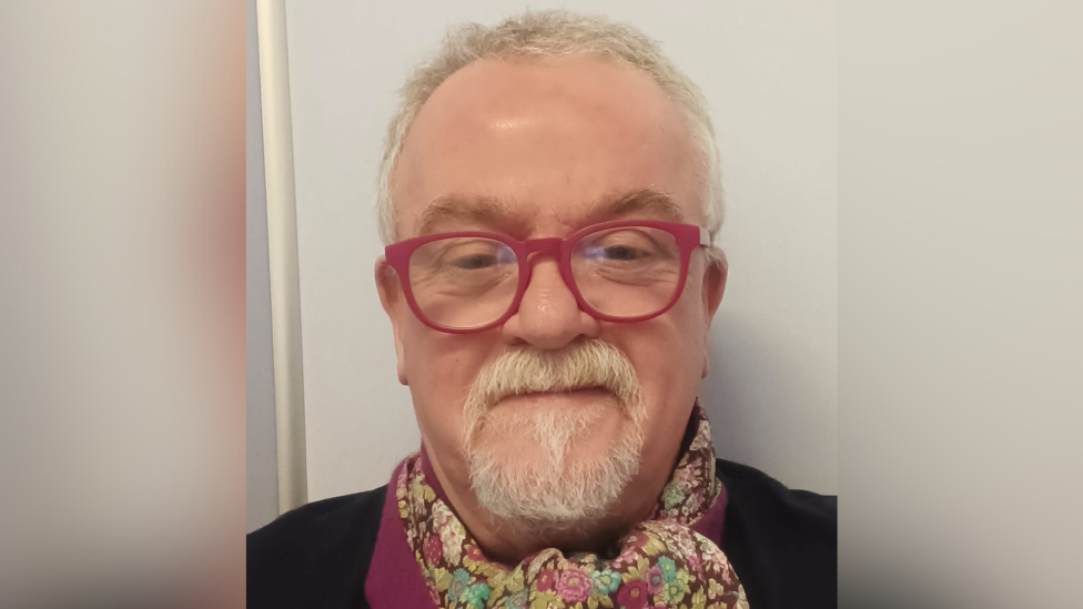 Jude Whyte - A man with white hair and goatie wearing red glasses taking a selfie