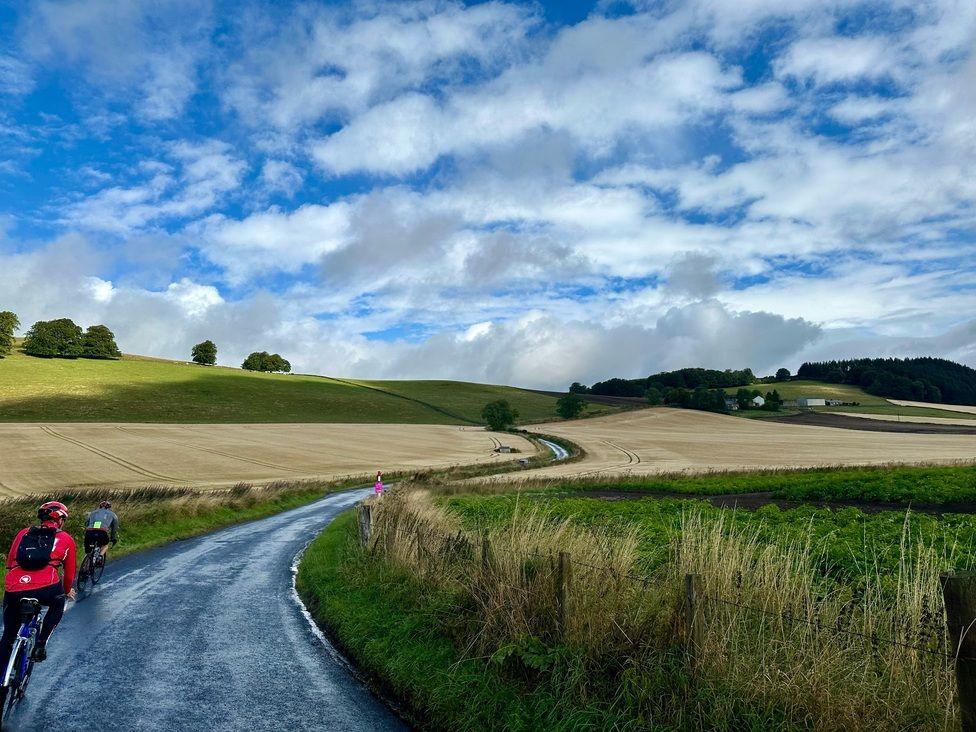 People cycling past fields looking north from Kinnordy