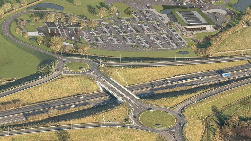 Artist impression of the proposed service station - showing an aerial view of two roundabouts on the motorway junction, to the north  is the service station with a large car park