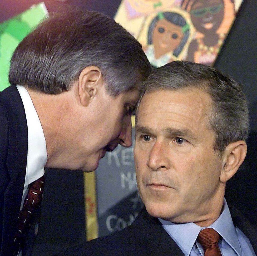 Former White House chief of staff Andy Card speaks quietly into the ear of the sombre-looking former US President George W Bush as he tells him about the 9/11 attacks.