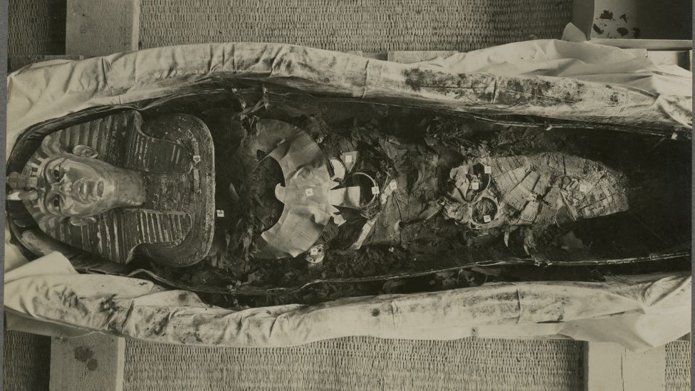 The mummified body of Tutankhamun, with the iconic burial mask on the face.