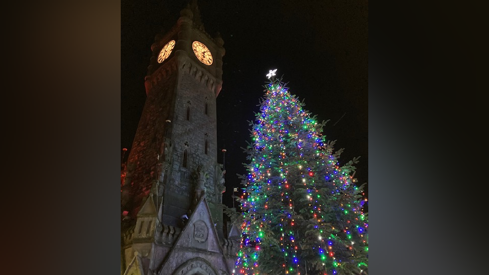 A lit up Christmas tree next to a church