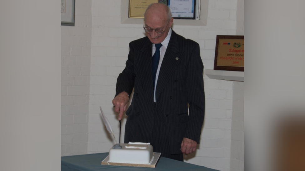 Image of Malcolm Wieck cutting a cake