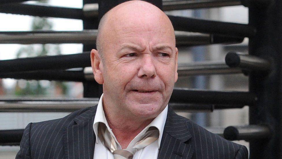 Liam Holden, pictured outside court before his death. He wears a pin stripe suit and a grey tie 