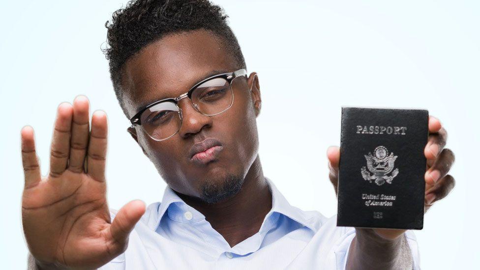 A man holding up his hand along with a US passport