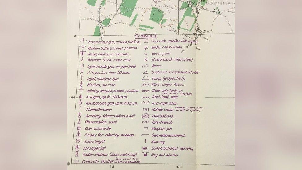 A key to a map. Written in purple, it explains the meanings of various symbols including strongpoint, searchlight and mines.