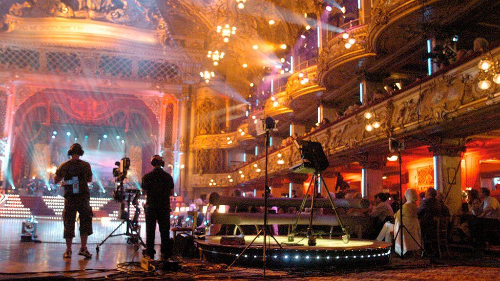 Camera crew filming in Blackpool's Tower Ballroom. The audience is looking on.