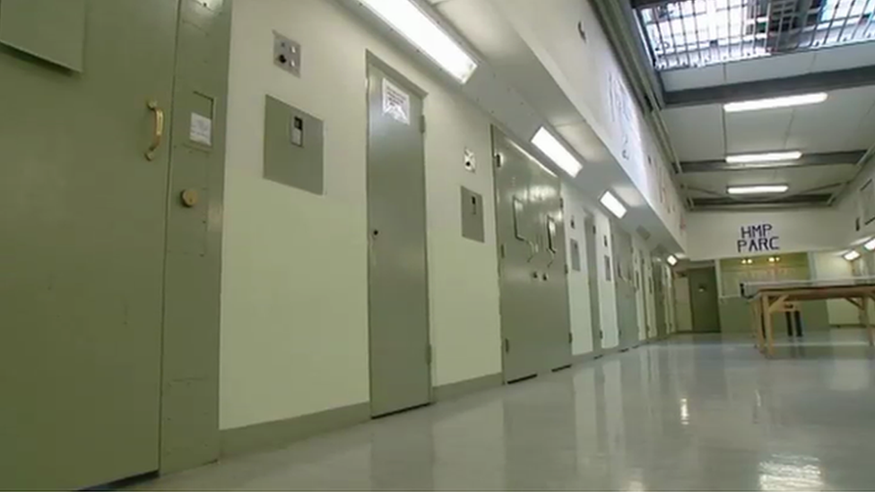 Inside Parc prison. metal doors with a slot in them in a corridor with hard floors and bars in a skylight above