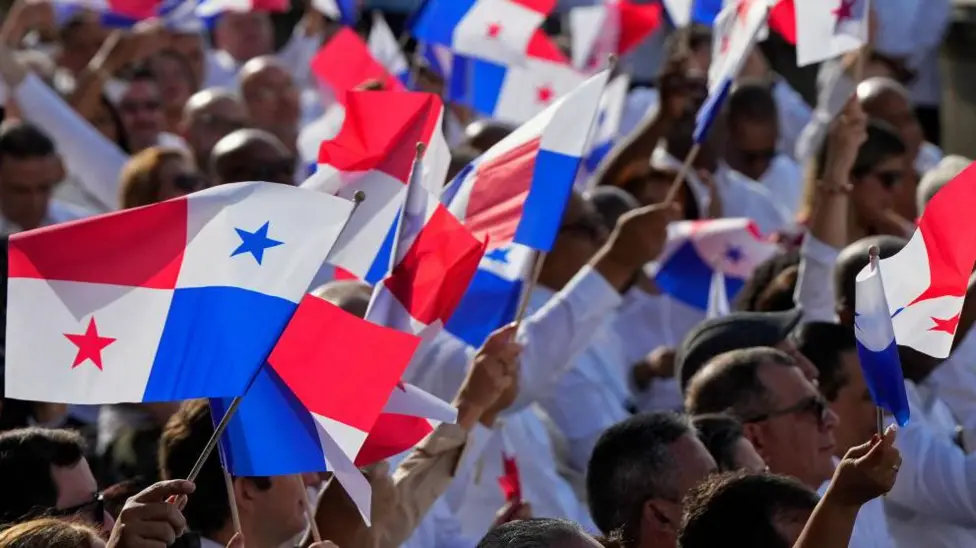 People in Panama wave flags to celebrate the anniversary of the handover of the Panama Canal